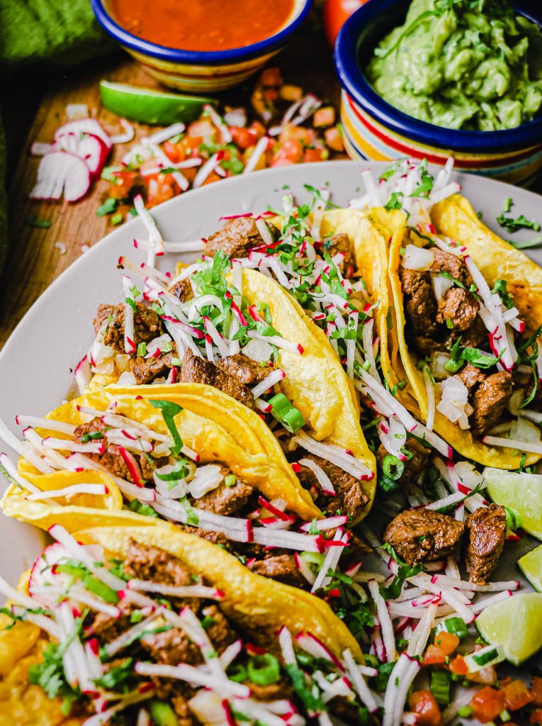 plate of Mexican street tacos with avocados