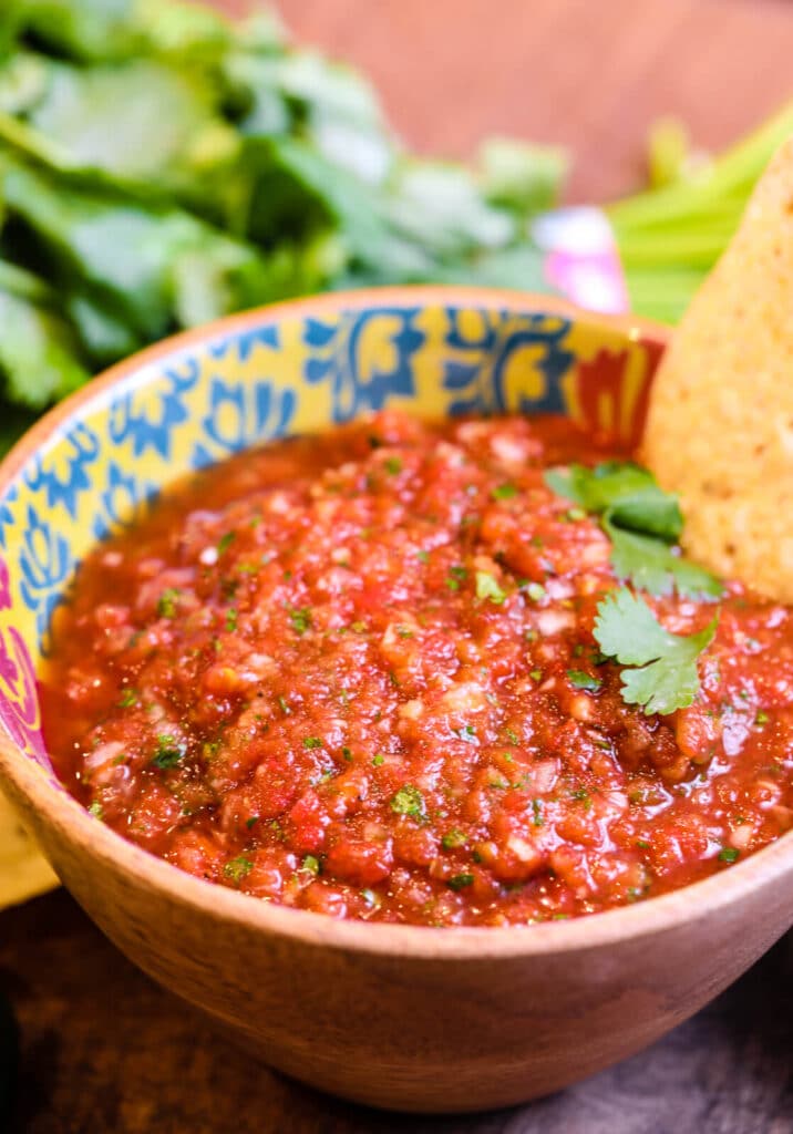 bowl full of restaurant style salsa with chips and cilantro