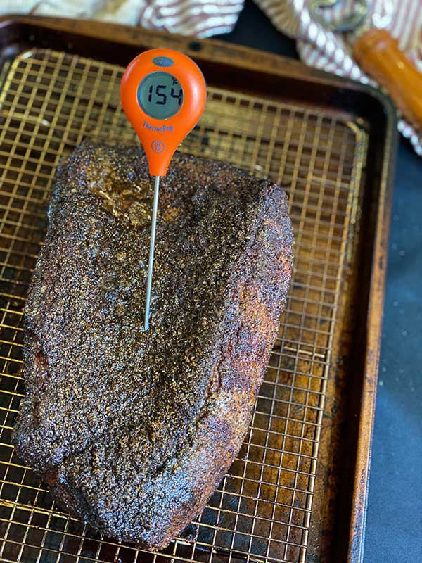 Smoked brisket on a cooling rack with Thermoworks Thermo Pop showing temperature of 154 degrees