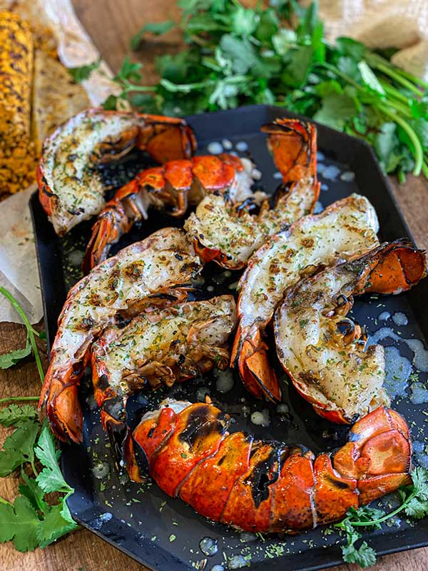 Grilled lobster tail halves plated with view of the seared lobster flesh and chipotle butter