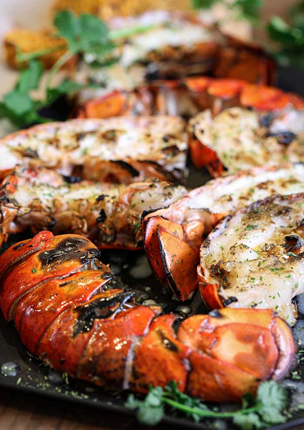 Grilled lobster tail halves with closeup of the seared lobster flesh that makes this method tasty