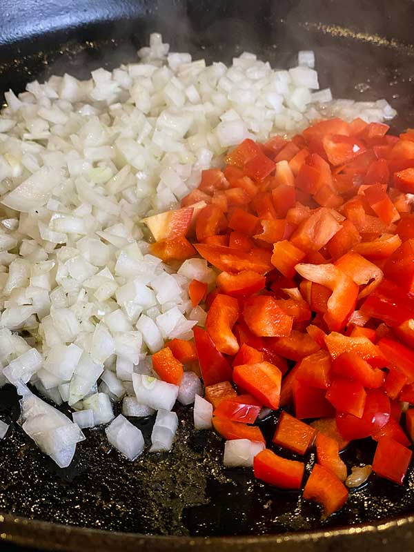 Onions and red peppers in cast iron skillet for Pan-fried Smoked Chicken Paprikash