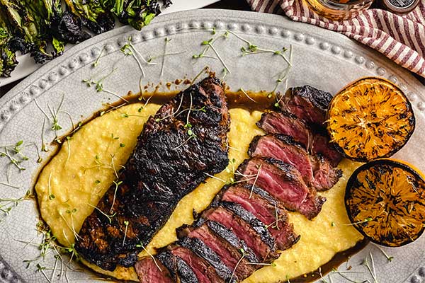 Bourbon marinated strip steak, grilled and served on a bed of polenta with grilled oranges