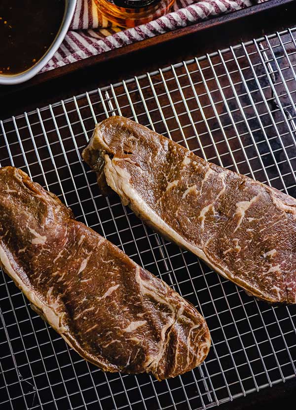 Bourbon marinated strip steak on a rack, patted dry