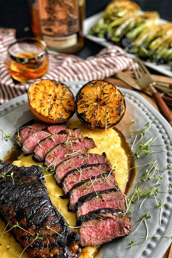 Grilled bourbon marinated strip steak, sliced and served on a bed of polenta