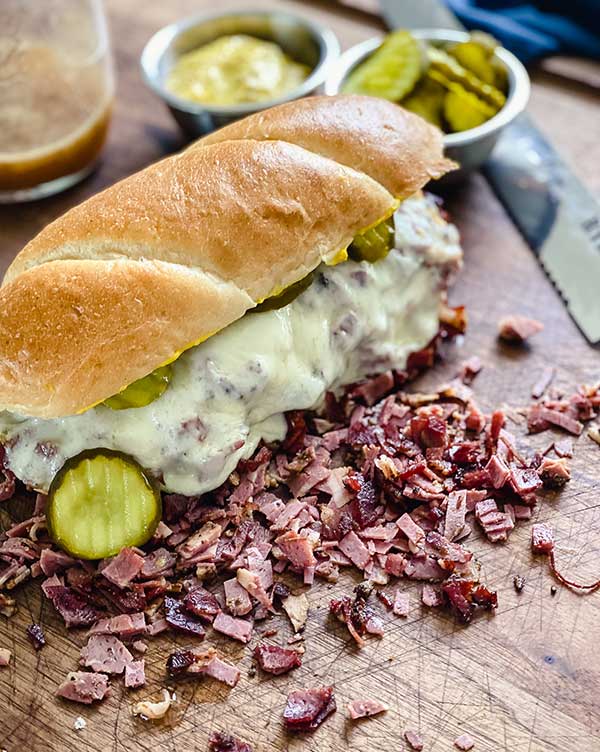 French dip pastrami sandwich on a cutting board