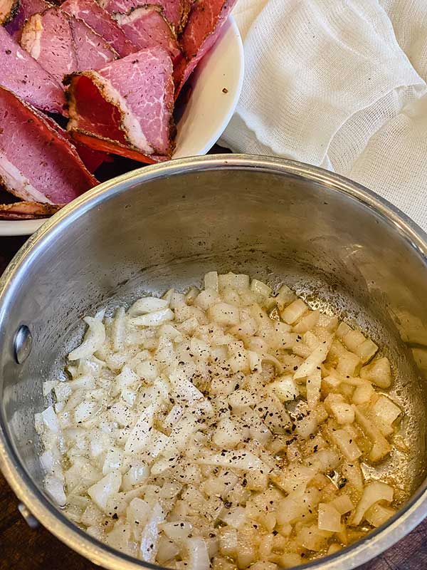 a pan with onions, butter, cracked pepper and coriander for au jus