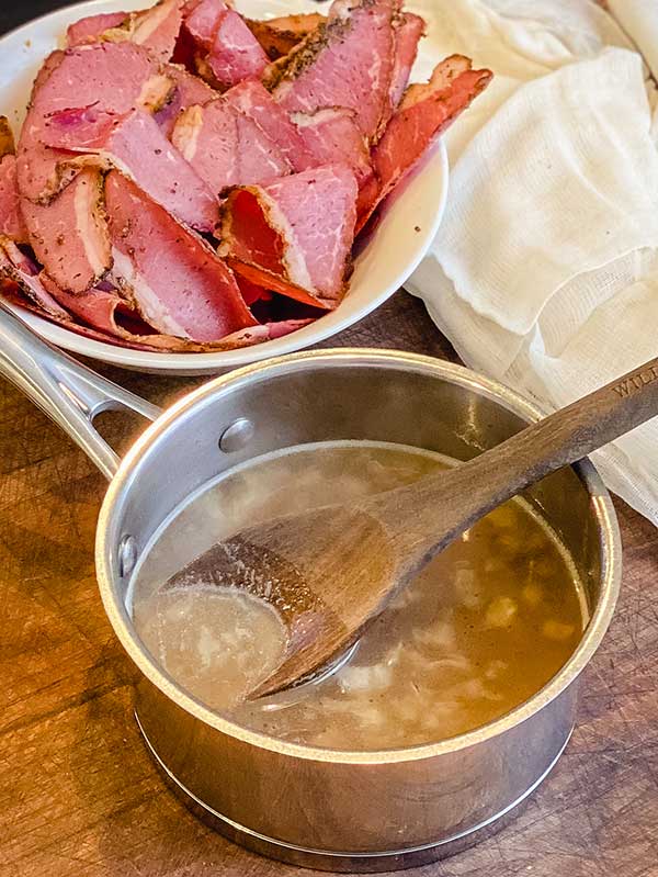 pan of au jus cools on counter with wooden spoon