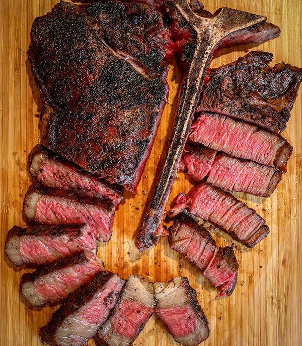 reverse seared porterhouse steak on cutting board with variety of consistent doneness