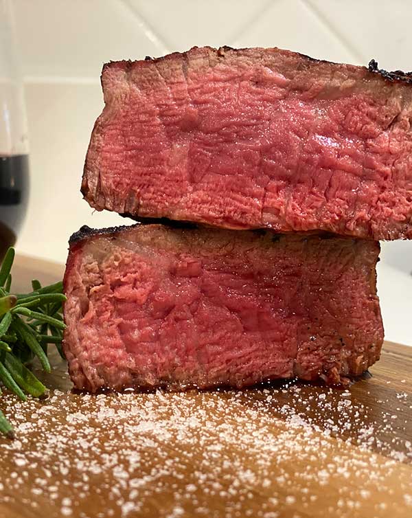 reverse seared steak with a perfect level of doneness on a cutting board