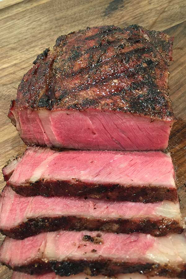 reverse seared steak, sliced on cutting board and perfectly pink inside