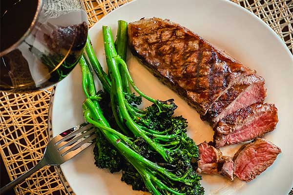 Grilled broccolini on a plate with steak