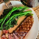 Grilled broccolini on a plate with steak