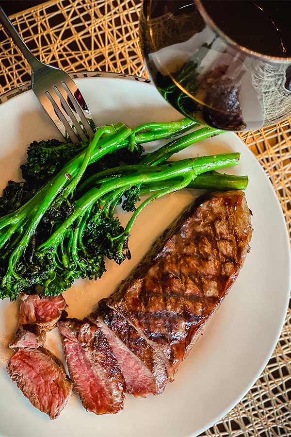 Grilled broccolini on a plate with steak