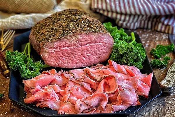 Smoked eye of round roast beef on a platter, sliced and pink