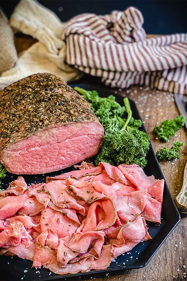 a platter of smoked cut of round roast beef, thinly sliced for sandwiches