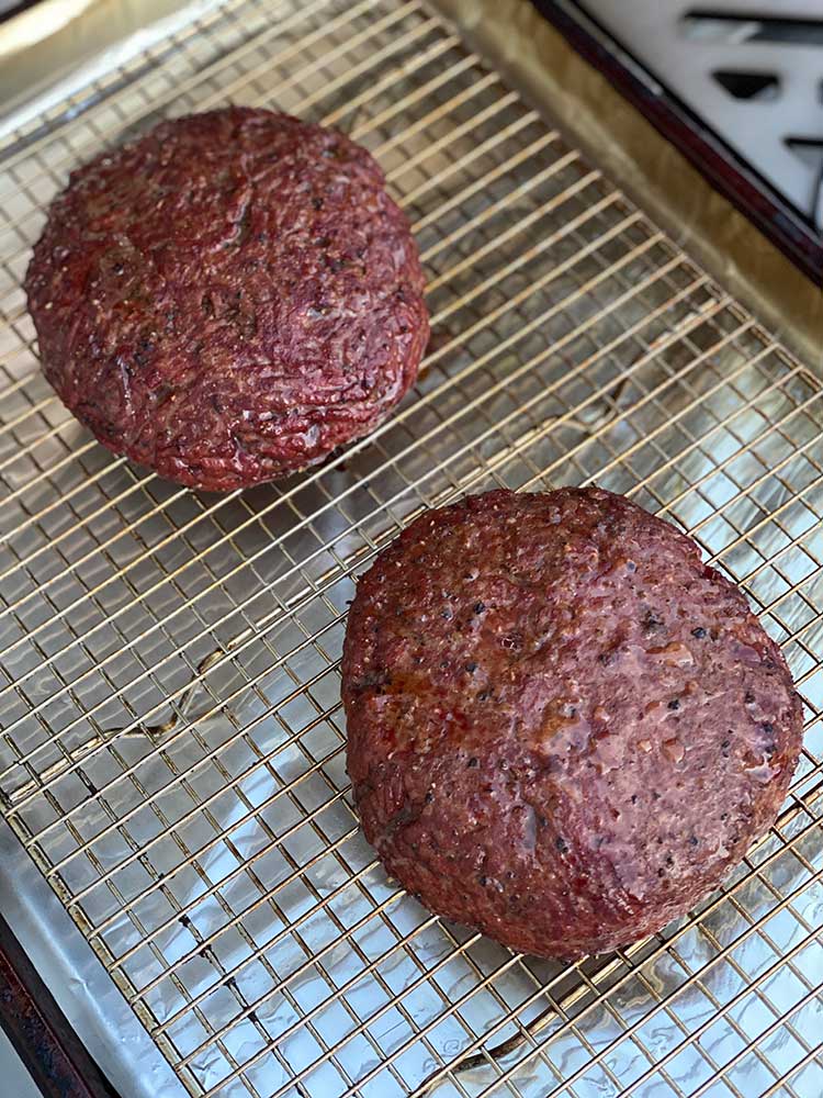 smoked burger patties resting on a wire rack