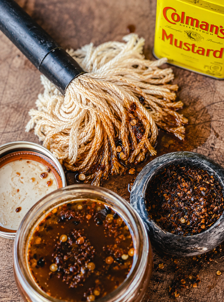 East Carolina mop sauce on a mop, sitting on a wooden cutting board.