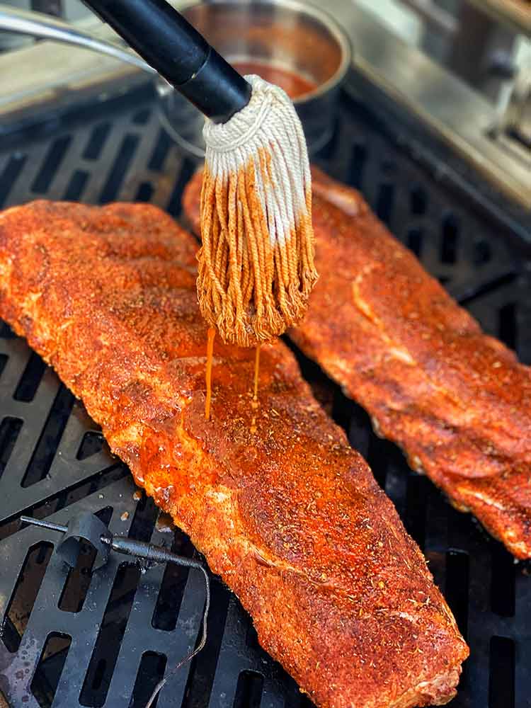 mopping baby back ribs with warm mop sauce