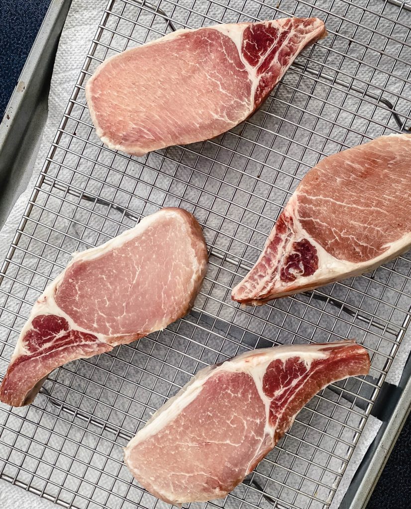 uncooked pork chops on a wire cooling rack