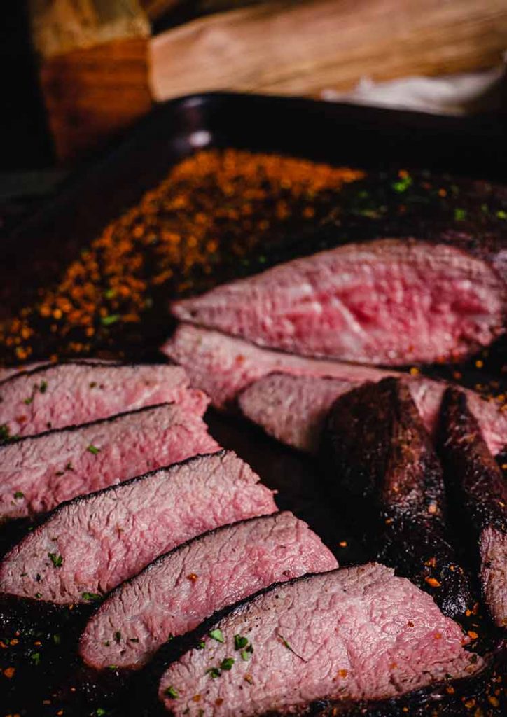 primo piano della tri-tip affettata, cotta rara e affettata contro il grano