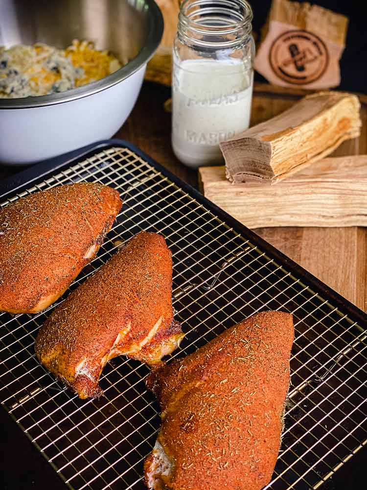 Season the chicken breasts evenly with flavorful rub and set on tray.