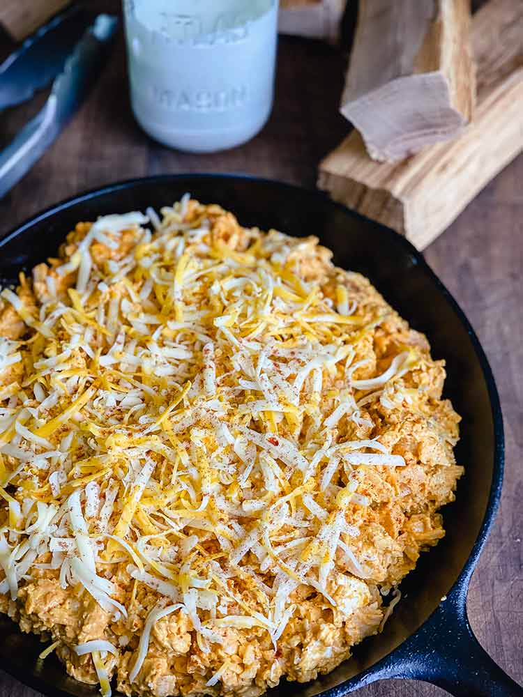 Chopped chicken breast covered with cheese in cast iron pan