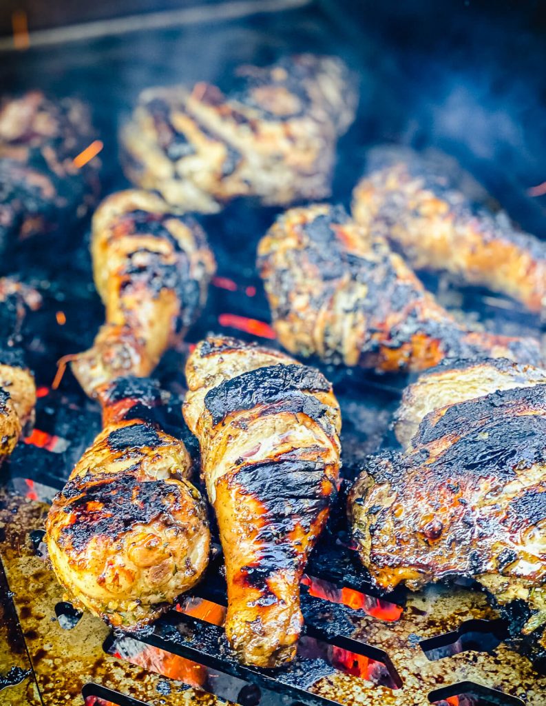 Caribbean jerk chicken being grilled over fire