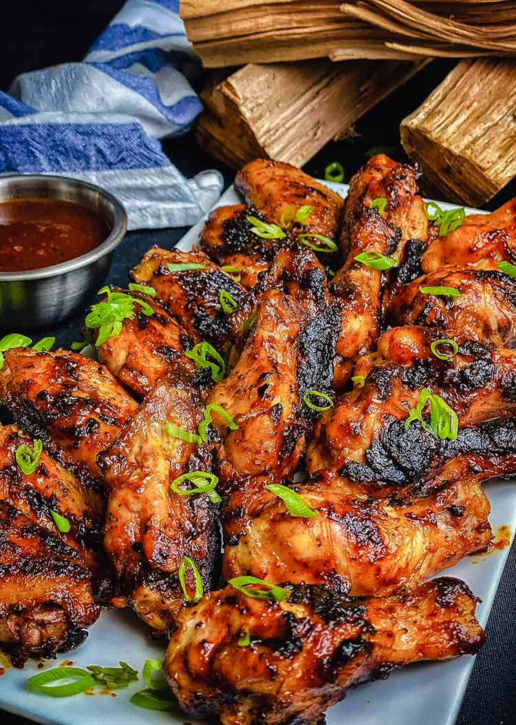 Memphis style chicken wings on a platter with mop sauce on the side