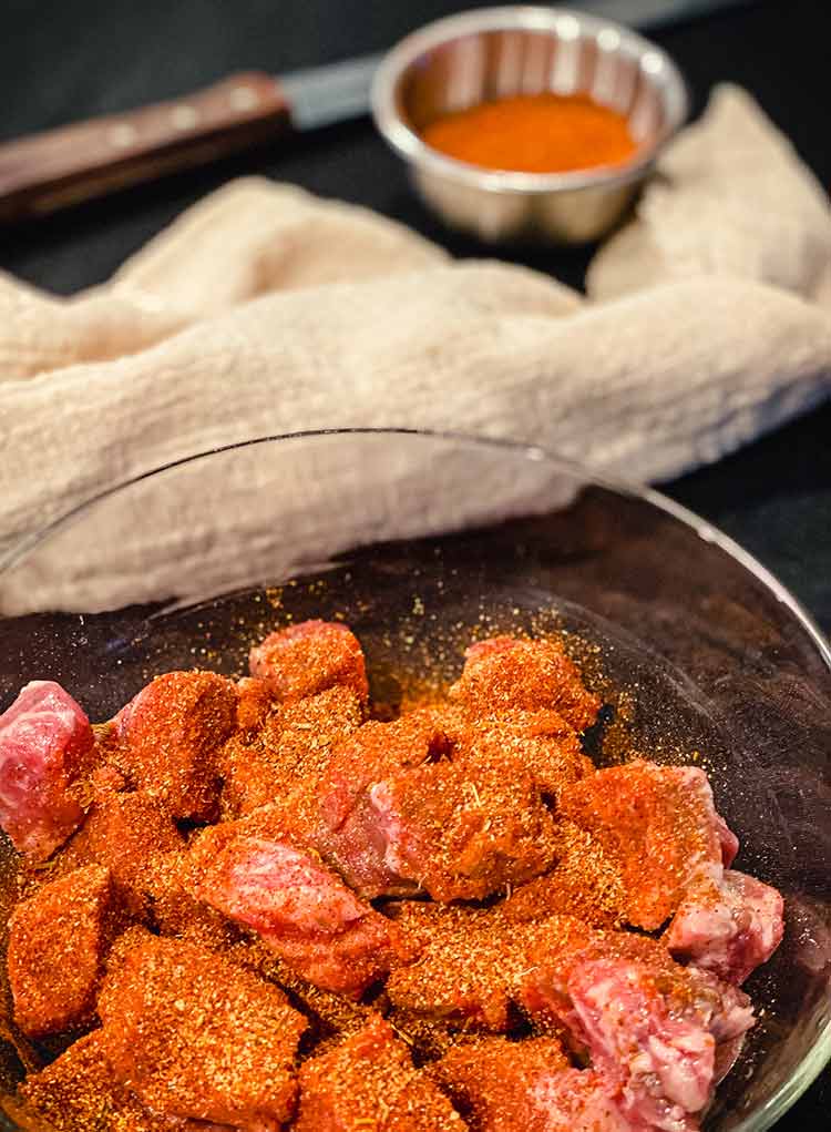 steak bites mixed with seasoning in a glass bowl