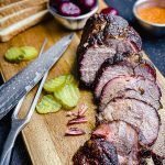 smoked coppa roast on a cutting board with sandwich fixings