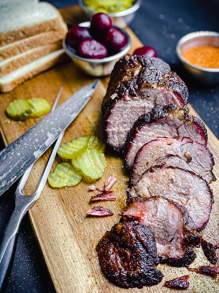 smoked coppa roast on a cutting board with sandwich fixings