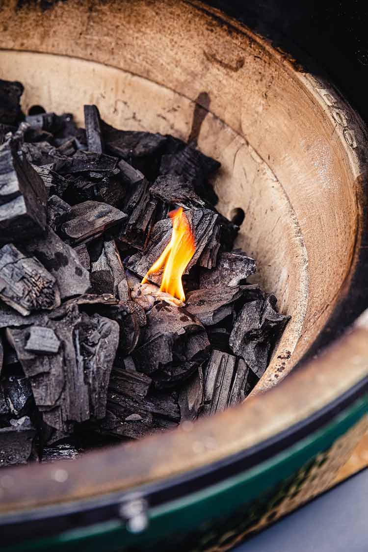Hardwood charcoal and a flame burning in a dome grill 