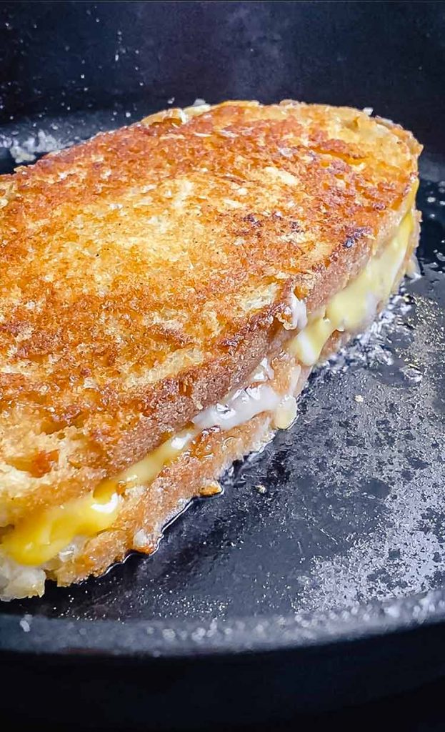 Cheese melting between two slices of bread in a skillet
