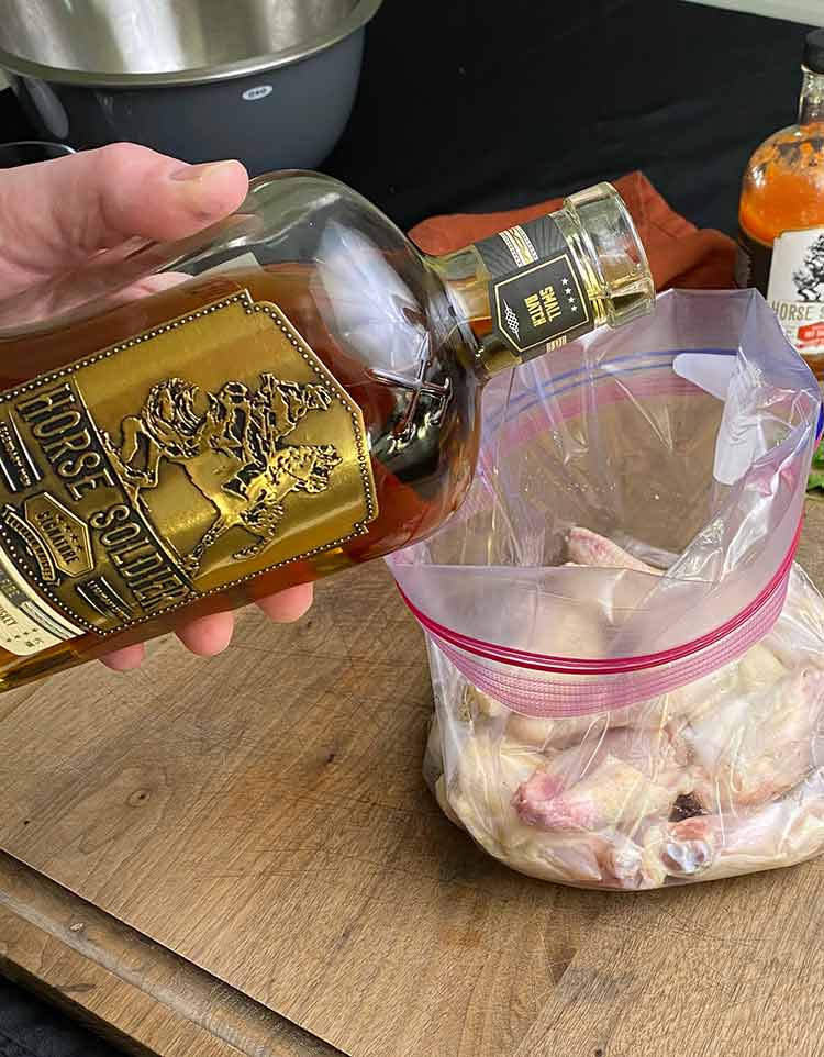 adding bourbon to a bag a chicken to marinade it