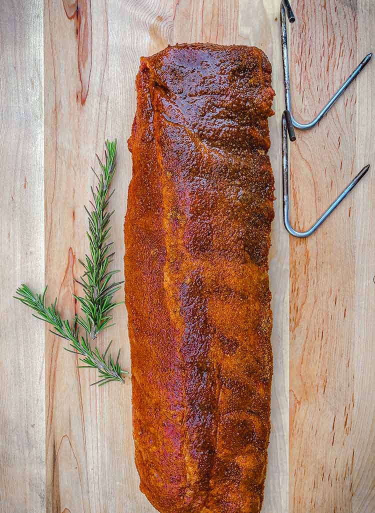 meat hooks and a rack of ribs on a cutting board