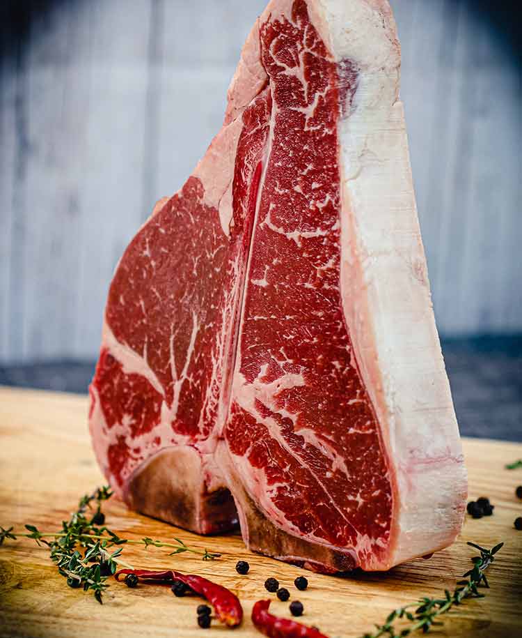 porterhouse standing on edge, thick, raw, and ready to cook