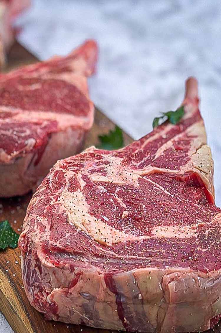 steak on a cutting board, seasoned with salt and pepper