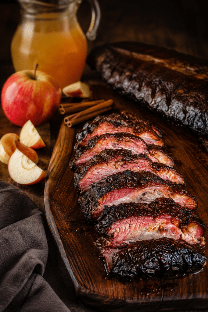 apple cinnamon brined baby back ribs on a platter with a sliced apple in the background