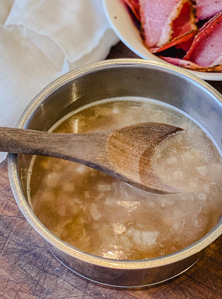 au jus gravy in a saucepan with spoon