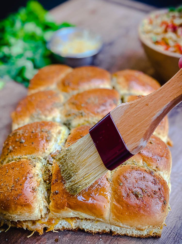 brushing on butter sauce for chicken enchilada sliders recipe