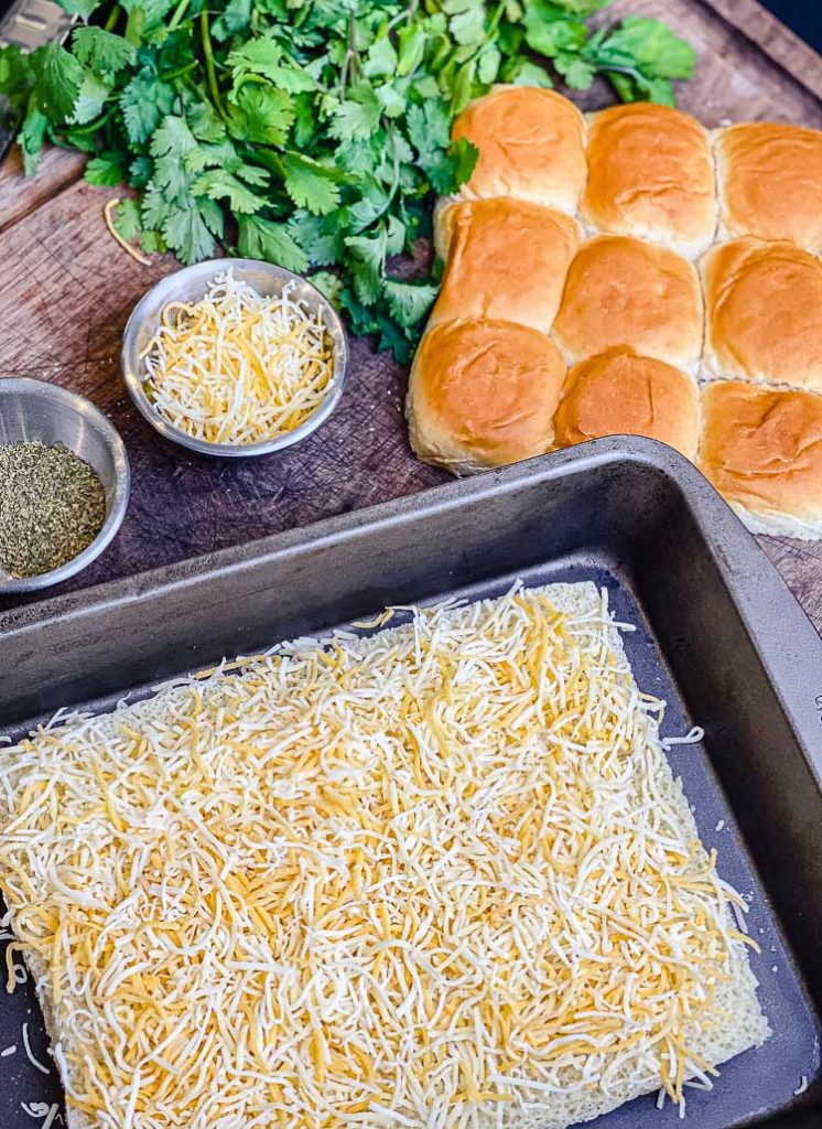 cheese being spread on bread for chicken enchiladas sliders recipe