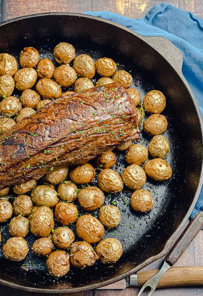 cooked chateaubriand in a cast iron skillet with potatoes