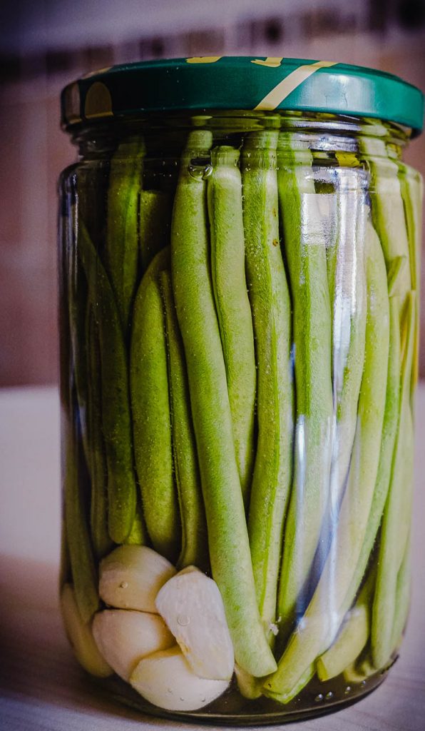 pickled green beans in a glass jar with garlic