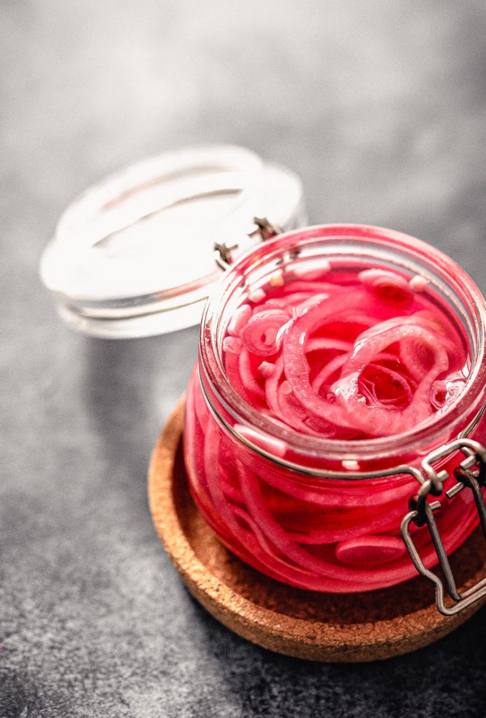 pickled red onions in an open jar with a latch