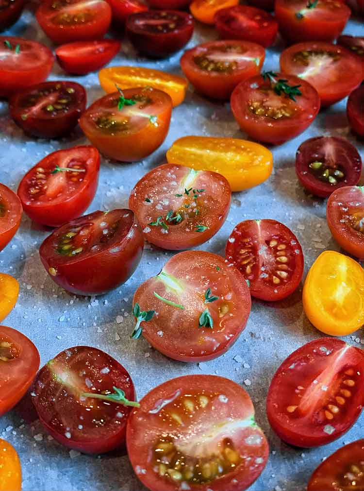 spices sprinkled on pan of sliced cherry and grape tomatoes