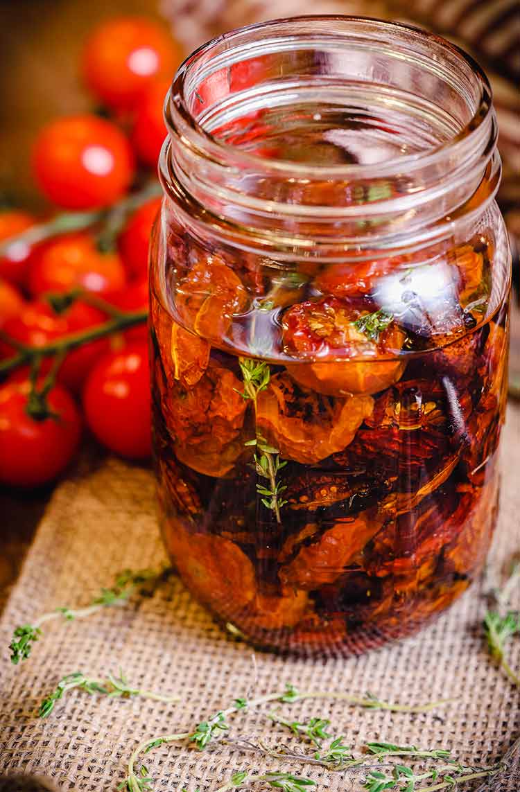 open mason jar filled with roast tomatoes and olive oil 