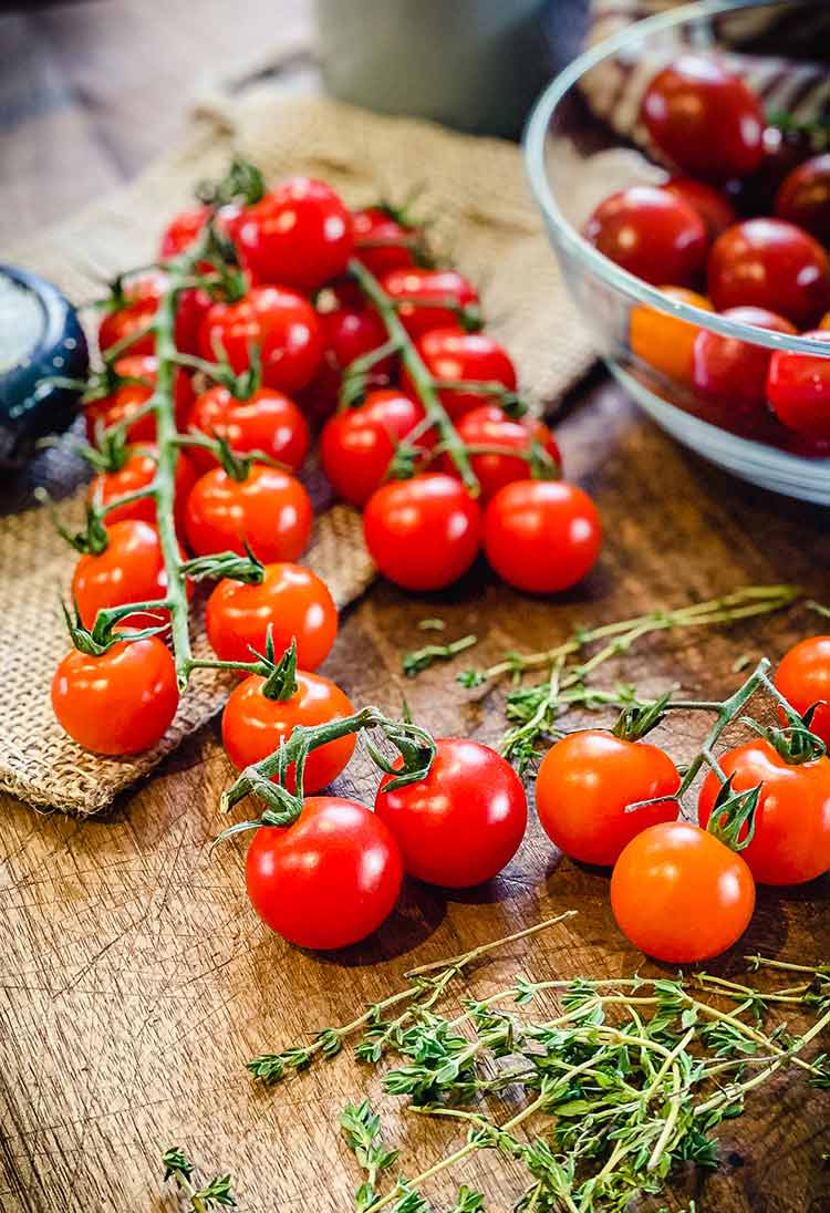 cherry tomatoes and sprigs of thyme on wooden cutting board