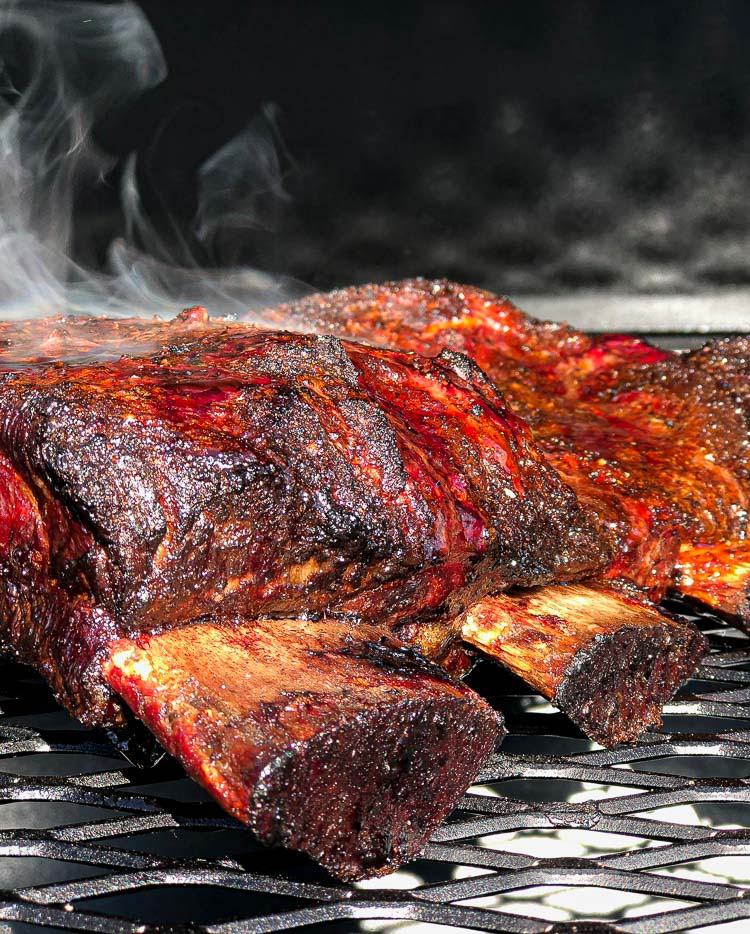 rack of beef short ribs smoking on grill