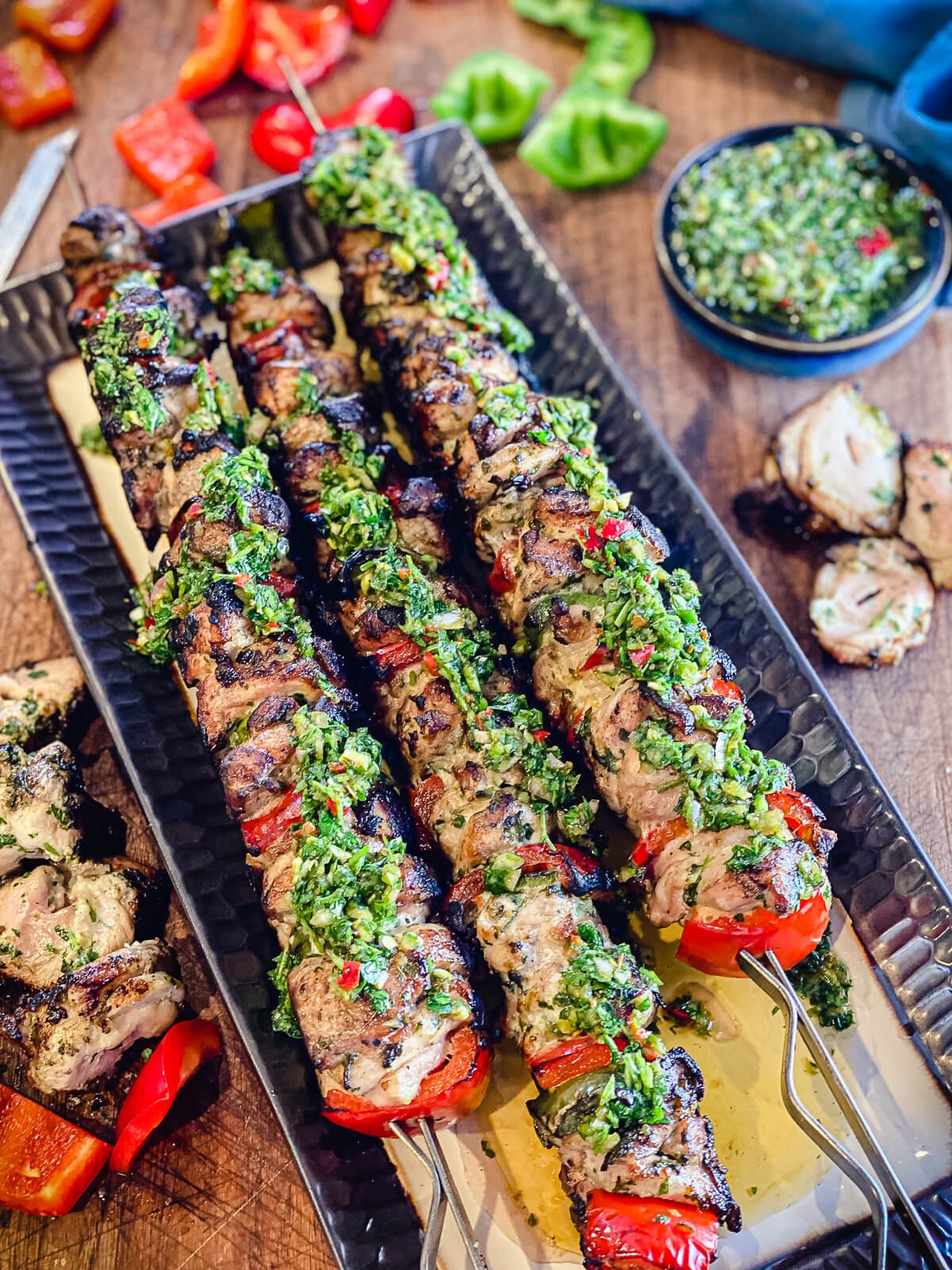 grilled chicken kabobs on a platter with chimichurri